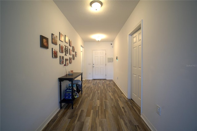 hall featuring dark wood-type flooring and baseboards