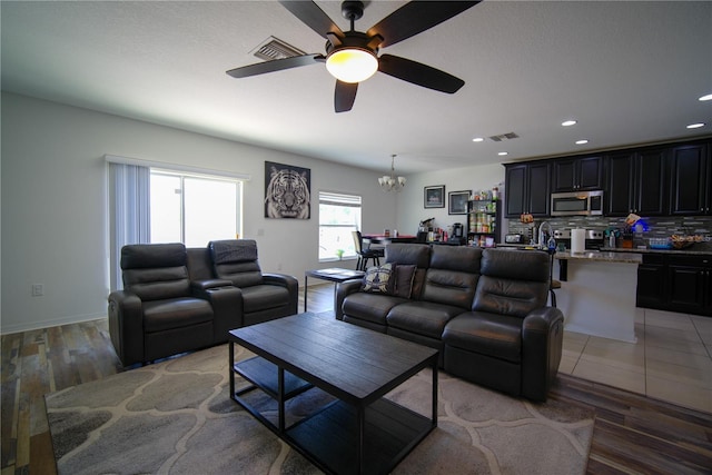 living room with recessed lighting, ceiling fan with notable chandelier, light wood-type flooring, and visible vents