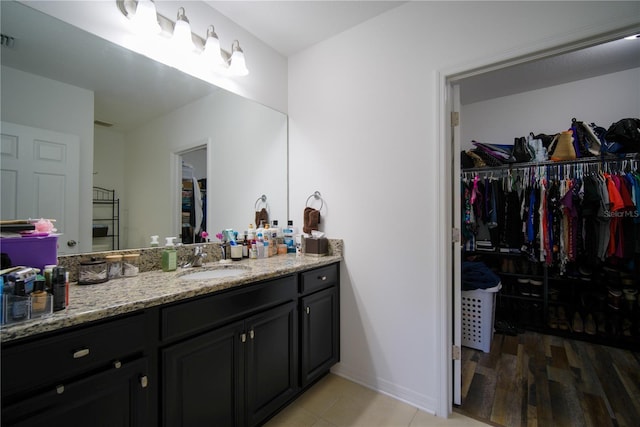 bathroom featuring visible vents, vanity, tile patterned floors, baseboards, and a spacious closet