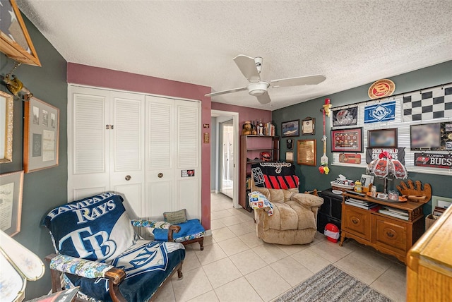living area featuring tile patterned flooring, a textured ceiling, and ceiling fan
