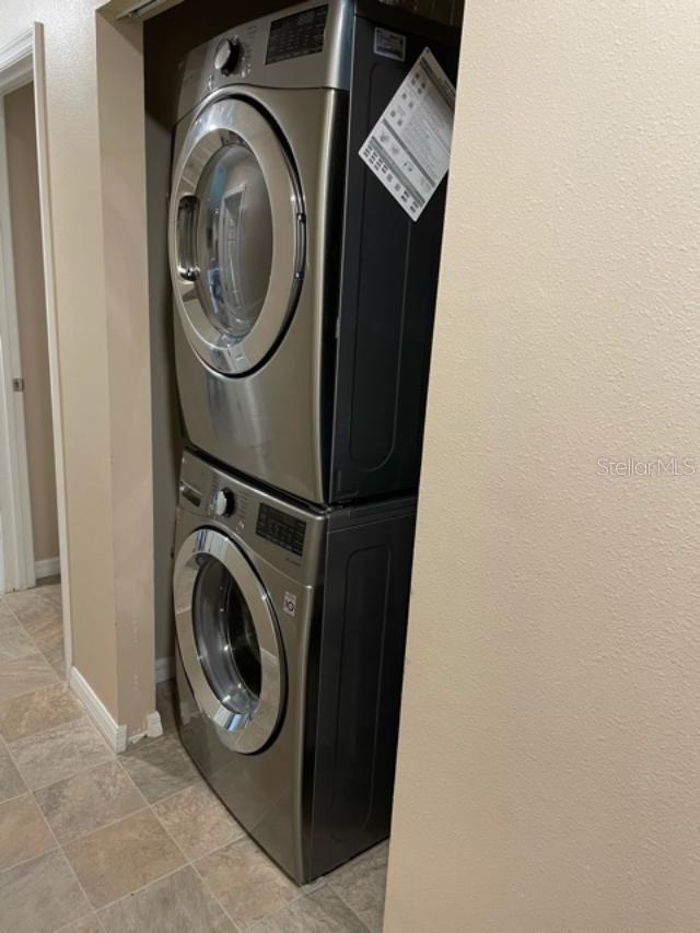 1 Pecan Course Cir, Ocala, FL 34472 - laundry room with stone finish flooring, laundry area, stacked washing maching and dryer, and baseboards