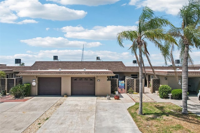 ranch-style home with driveway, fence, an attached garage, stucco siding, and a gate