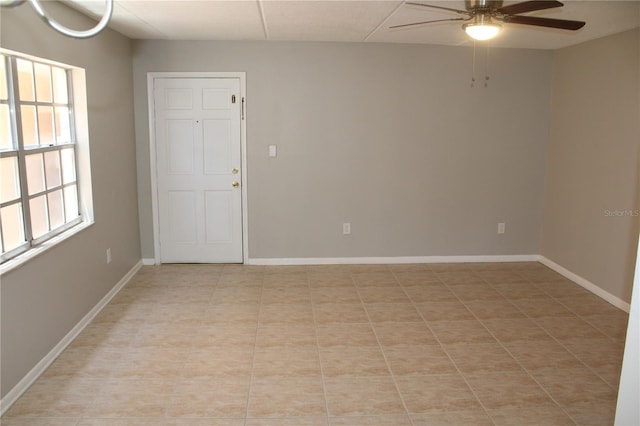 empty room featuring baseboards, a ceiling fan, and light tile patterned floors