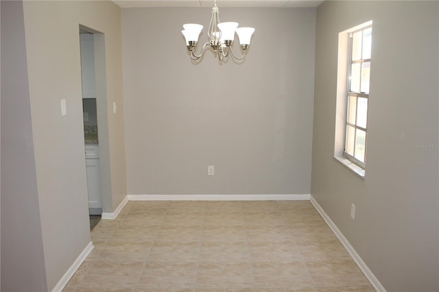 unfurnished room with baseboards, a wealth of natural light, and a notable chandelier