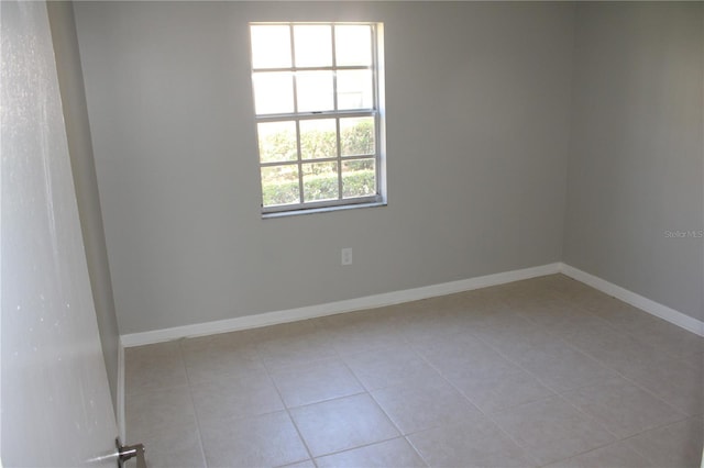 tiled spare room featuring baseboards