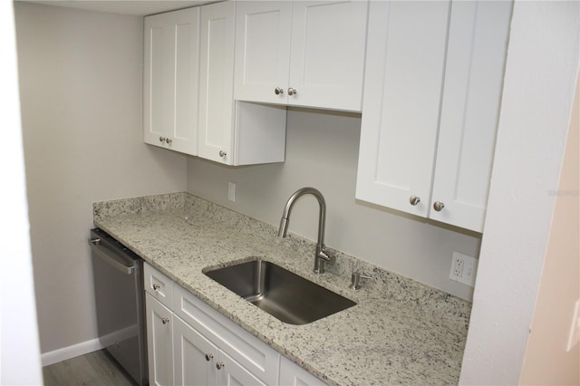 kitchen featuring dishwasher, a sink, light stone counters, white cabinets, and baseboards