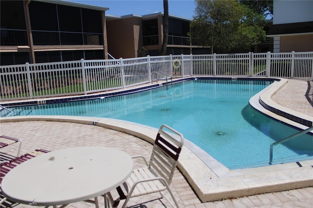 community pool with fence and a patio area