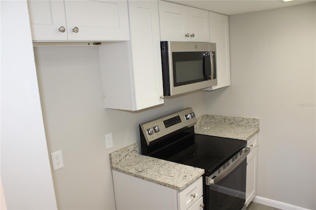 4725 Joseph Ct Unit 233, Tampa, FL 33614 - kitchen with stainless steel appliances, white cabinetry, light stone countertops, and baseboards