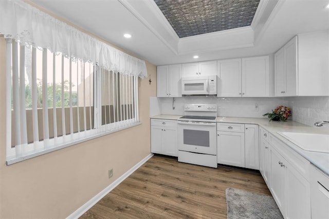 kitchen with white appliances, a raised ceiling, a sink, decorative backsplash, and crown molding