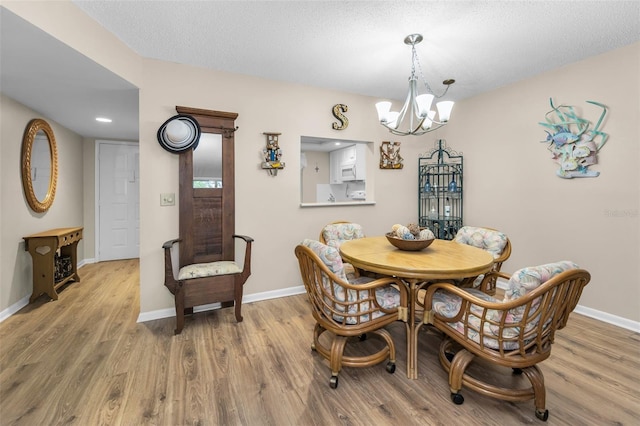 dining room with a chandelier, wood finished floors, baseboards, and a textured ceiling