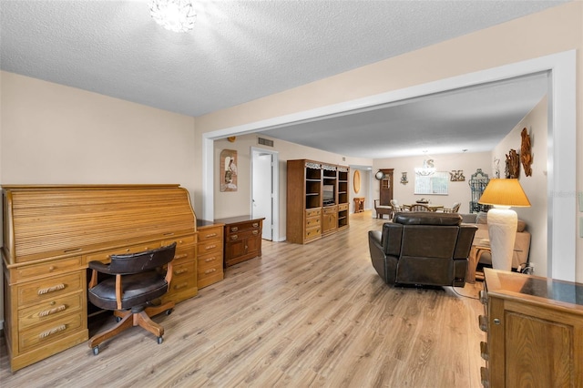 living room featuring light wood finished floors, a desk, and a textured ceiling