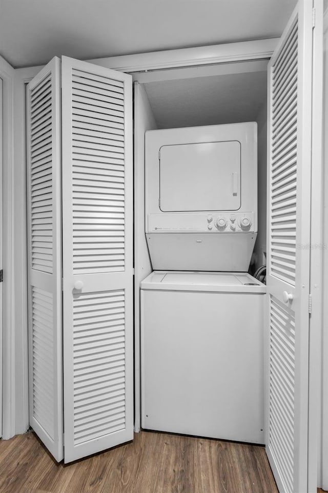 laundry room with stacked washer / drying machine and wood finished floors