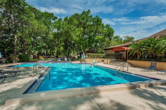community pool featuring a patio area and view of scattered trees