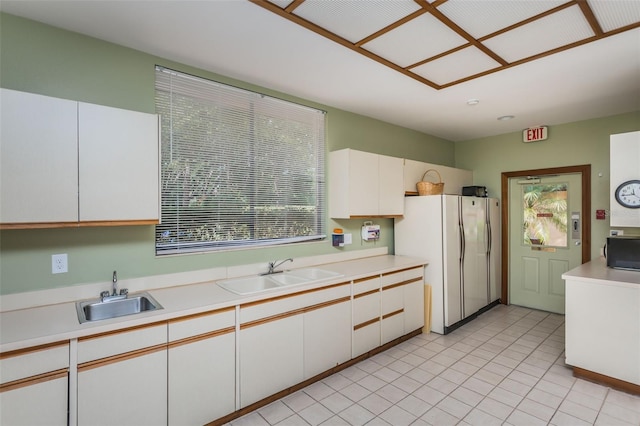kitchen with a sink, freestanding refrigerator, black microwave, and light countertops