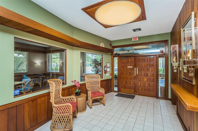 entryway with a wainscoted wall, wooden walls, and light tile patterned flooring