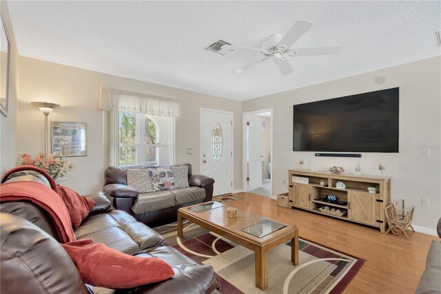 living room with visible vents, wood finished floors, baseboards, a textured ceiling, and a ceiling fan