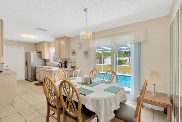 dining space with light tile patterned flooring, a notable chandelier, visible vents, and a textured ceiling