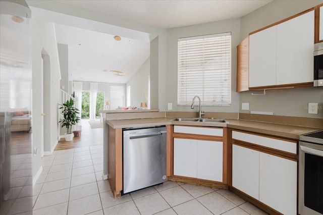 6260 Olivedale Dr, Riverview, FL 33578 - kitchen featuring appliances with stainless steel finishes, a sink, white cabinetry, light tile patterned floors, and a peninsula