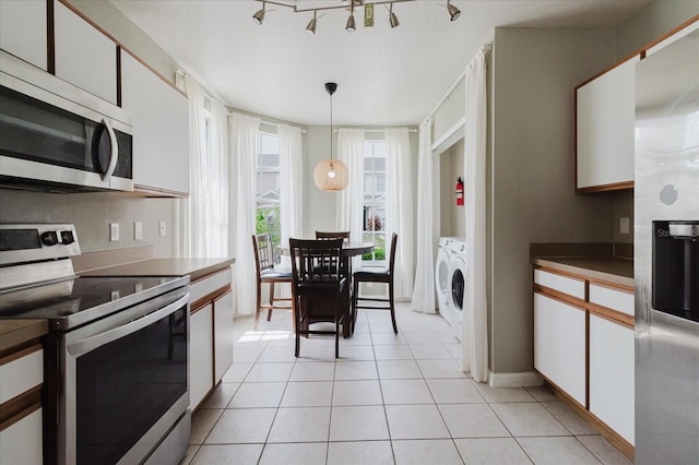 6260 Olivedale Dr, Riverview, FL 33578 - kitchen with appliances with stainless steel finishes, washer and clothes dryer, white cabinets, light tile patterned floors, and decorative light fixtures