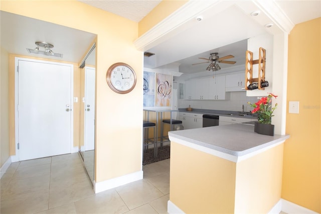 kitchen with baseboards, a sink, decorative backsplash, and a ceiling fan