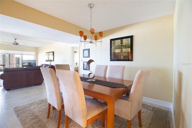 dining space with baseboards, ceiling fan with notable chandelier, and light tile patterned floors