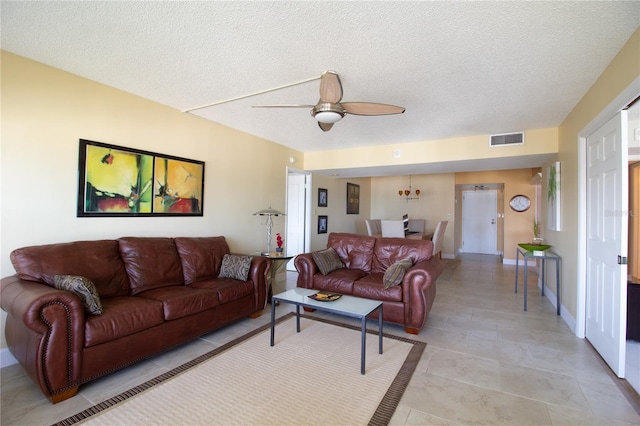 living area with light tile patterned floors, ceiling fan, a textured ceiling, and visible vents