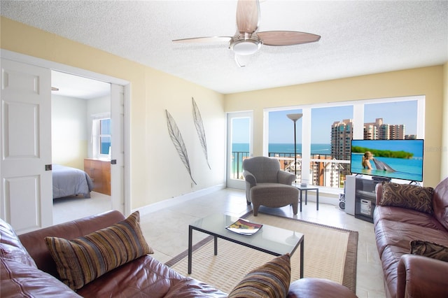 living area featuring a textured ceiling, ceiling fan, and light tile patterned floors