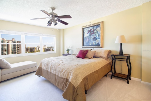 carpeted bedroom featuring baseboards, a ceiling fan, and a textured ceiling