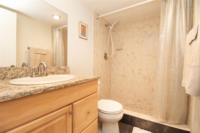 full bathroom featuring vanity, tile patterned floors, toilet, and tiled shower