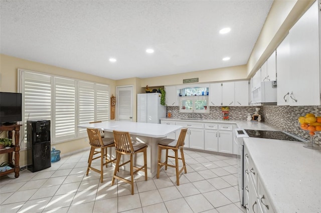 kitchen featuring white appliances, light tile patterned floors, decorative backsplash, and a sink