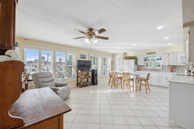 living room featuring a ceiling fan, recessed lighting, a textured ceiling, and light tile patterned flooring