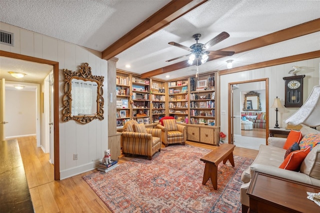 sitting room with a ceiling fan, a textured ceiling, visible vents, beam ceiling, and light wood-style flooring