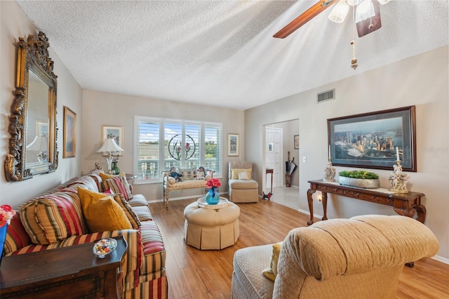 living area with visible vents, a textured ceiling, light wood-style floors, and ceiling fan
