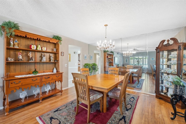 dining area featuring light wood-style floors, a textured ceiling, and a chandelier