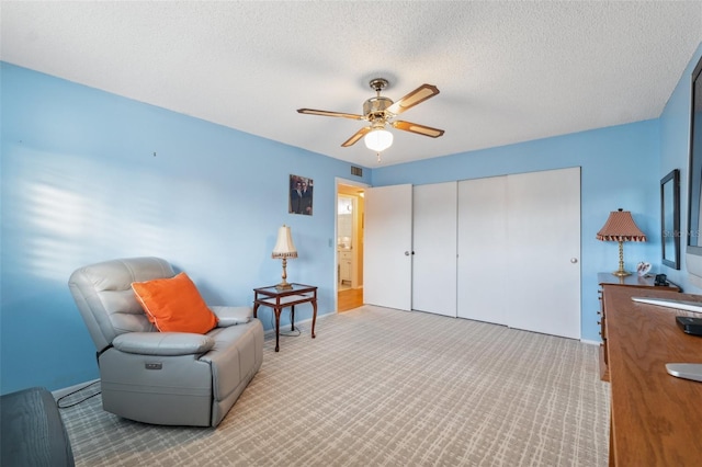 living area with a ceiling fan, a textured ceiling, visible vents, and carpet