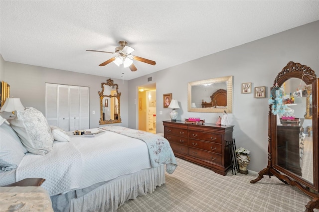 carpeted bedroom featuring a ceiling fan, visible vents, baseboards, a closet, and ensuite bathroom