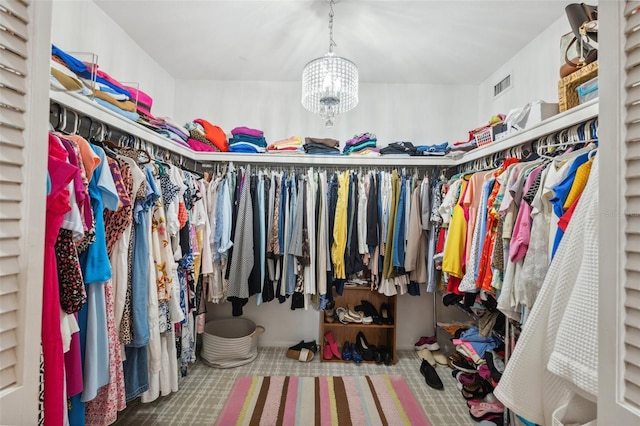walk in closet featuring a notable chandelier, visible vents, and carpet