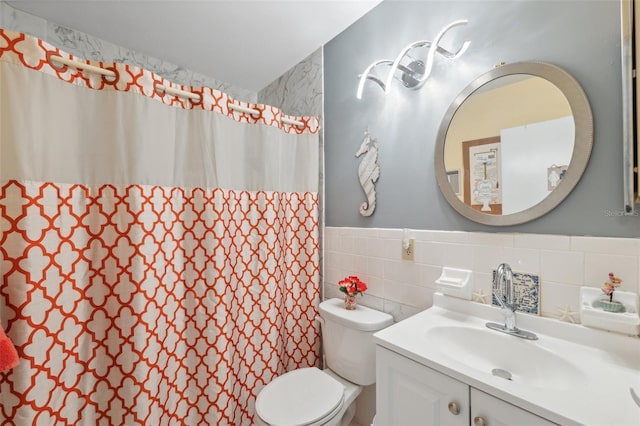 bathroom featuring vanity, toilet, tile walls, a shower with shower curtain, and a wainscoted wall