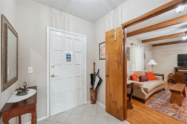 foyer featuring light tile patterned floors, a textured ceiling, ceiling fan, and baseboards