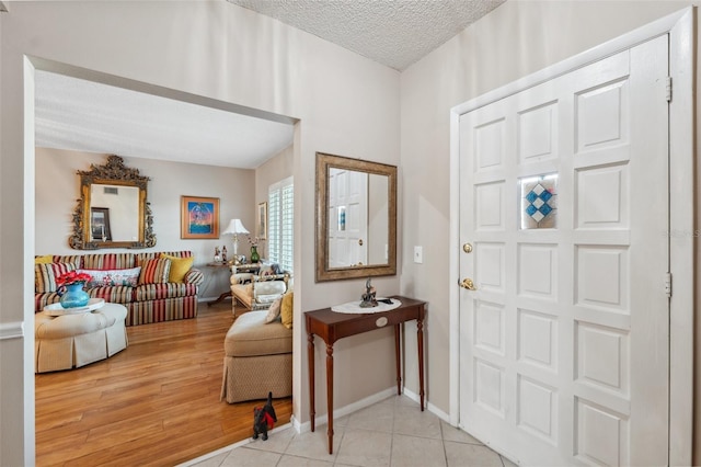 entryway with baseboards, a textured ceiling, and wood finished floors