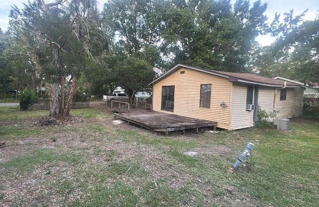 rear view of property featuring a lawn, a deck, and cooling unit
