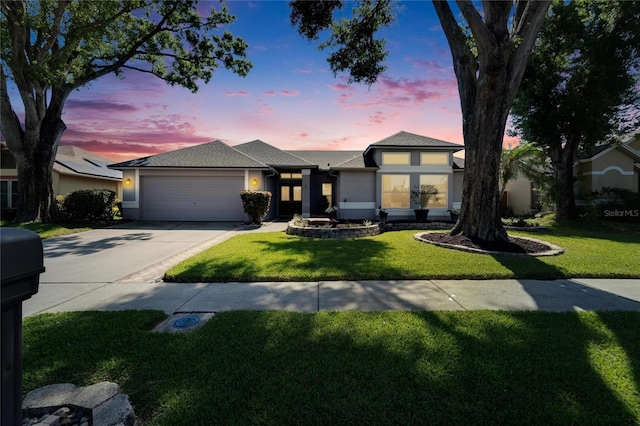 view of front of house featuring an attached garage, driveway, a front yard, and stucco siding