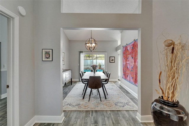 dining area with baseboards, wood finished floors, and a chandelier