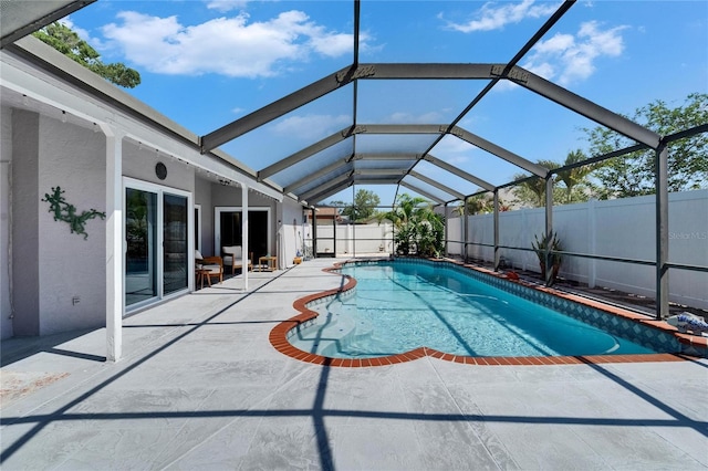 view of pool with a fenced backyard, a fenced in pool, a patio area, and glass enclosure