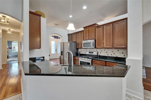 16516 Bridgewalk Dr, Lithia, FL 33547 - kitchen featuring light wood finished floors, stainless steel appliances, a peninsula, and decorative backsplash