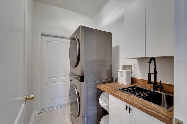 16516 Bridgewalk Dr, Lithia, FL 33547 - laundry area featuring cabinet space, light tile patterned floors, stacked washer / drying machine, and a sink