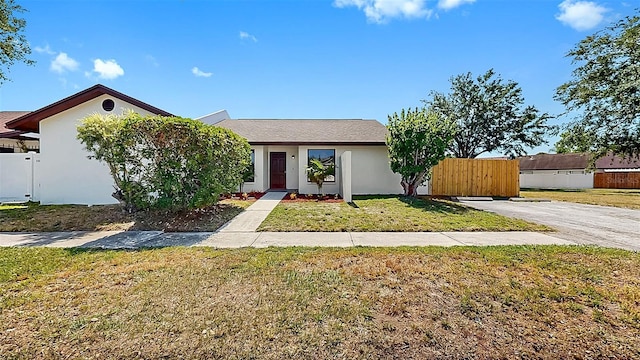 view of front of home featuring fence, stucco siding, and a front yard