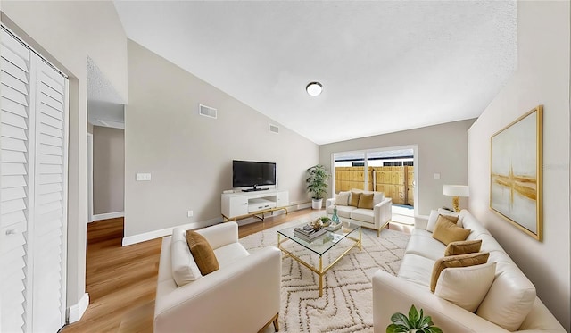 living room with high vaulted ceiling, visible vents, baseboards, and light wood finished floors