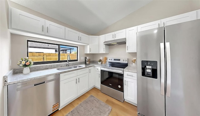 kitchen featuring appliances with stainless steel finishes, a sink, lofted ceiling, under cabinet range hood, and white cabinetry