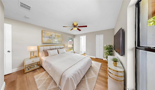 bedroom featuring baseboards, a ceiling fan, light wood-style flooring, and visible vents